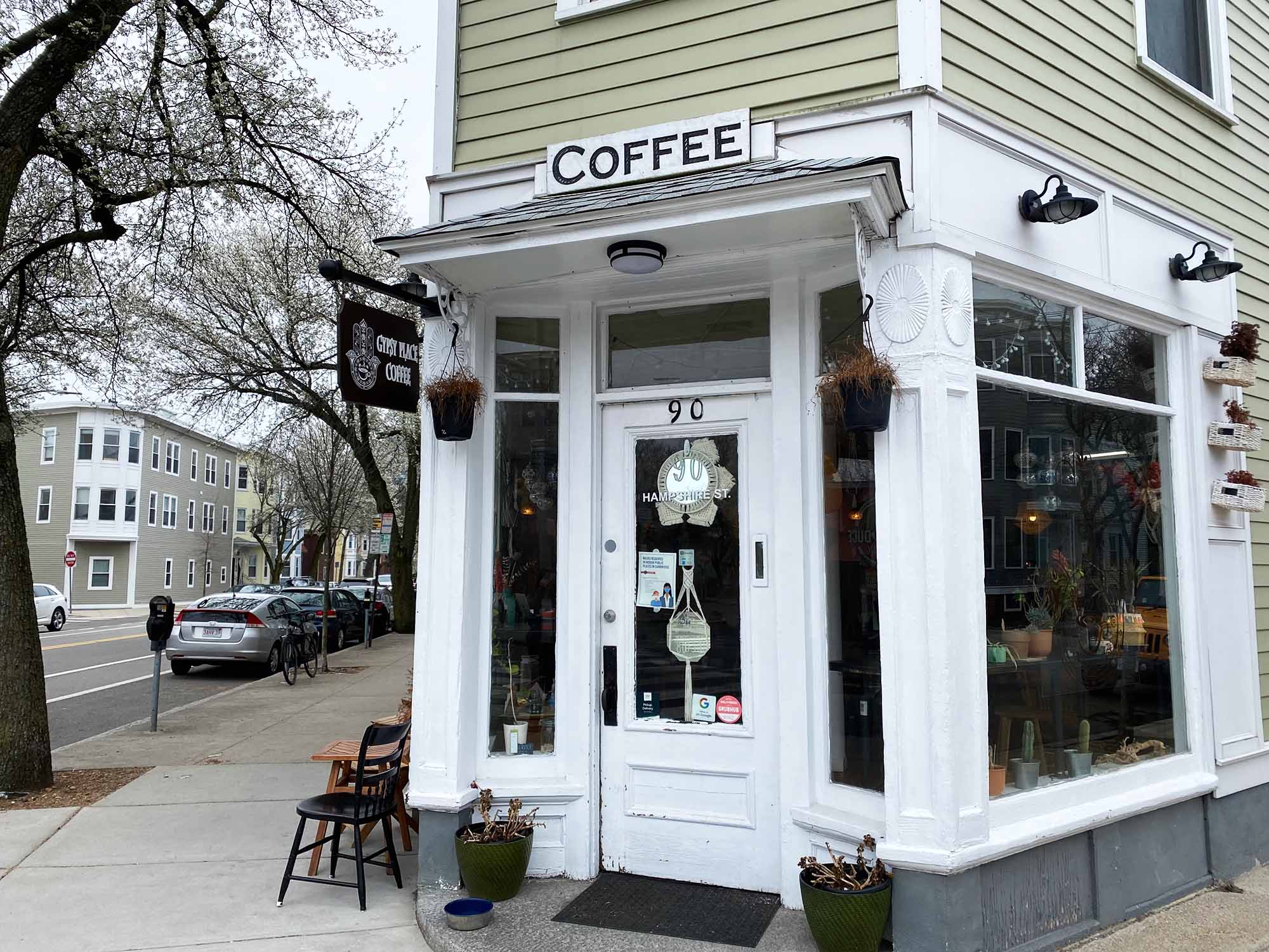 Photo of Gypsy Place Coffee and Juice Bar. The white, wooden entrance to a small cafe on the corner of an intersection is shown. Sign above door reads "Coffee".