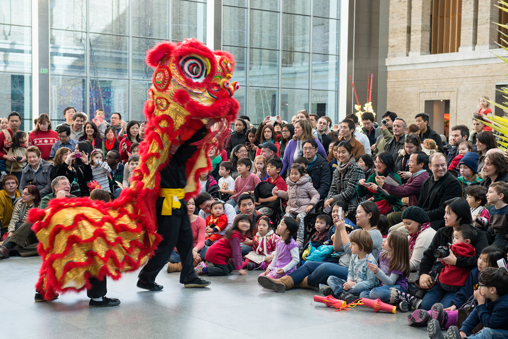 A crowd enjoys a performance feautring a red dragon at the MFA's Lunar New Year Celebration