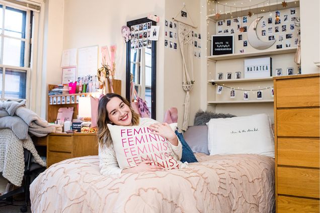 Natalie Held lays on her bed in her dorm room and holds her "feminist" pillow