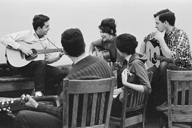 Students gather around with guitars and sing 