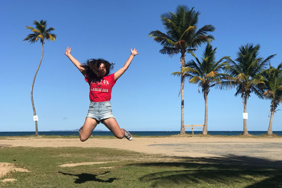 Kyle Schultz doing the High School musical jump on the beach with palm trees and a blue sky in the background