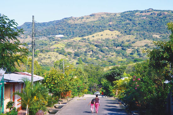 two people walking down a street towards a mountain