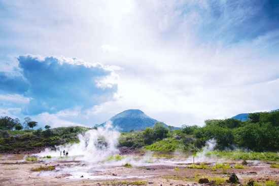 a volcano in the distance with fog and smoke in the foreground