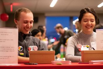 Matthew Walker and Caroline Jens sitting behind a red table and laughing