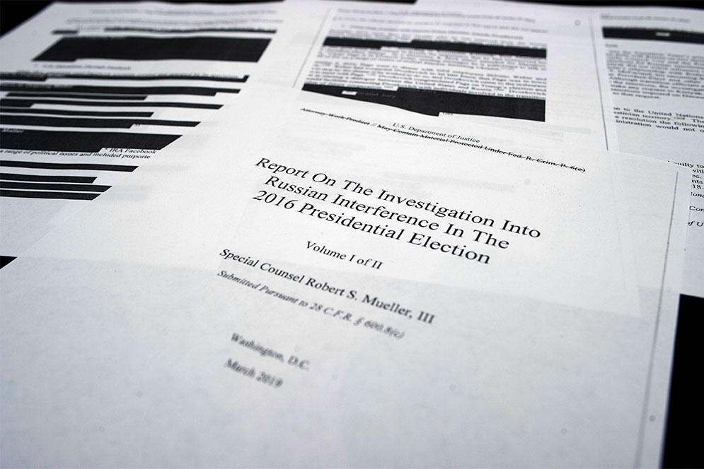 Photo of a paper copy of the redacted Mueller Report with cover page up front.