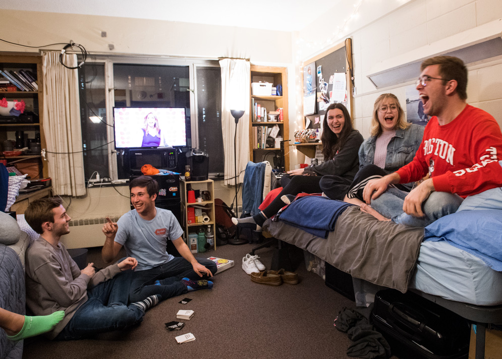 Students laugh while they play cards in a dorm room