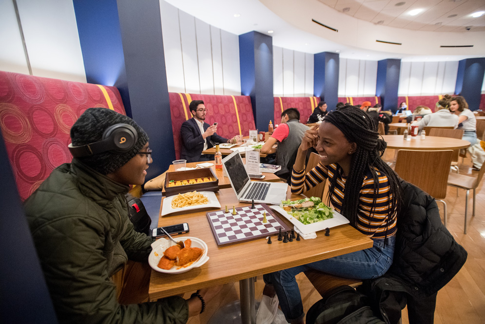 Two students, who are dating, play chess together at Bay State Underground