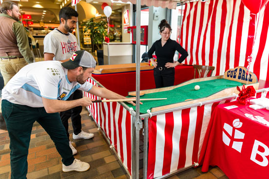student preparing to hit a cue ball at a carnival booth