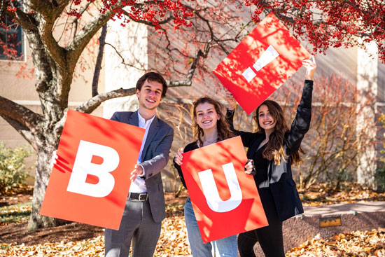 three students holding cards with B, U and !