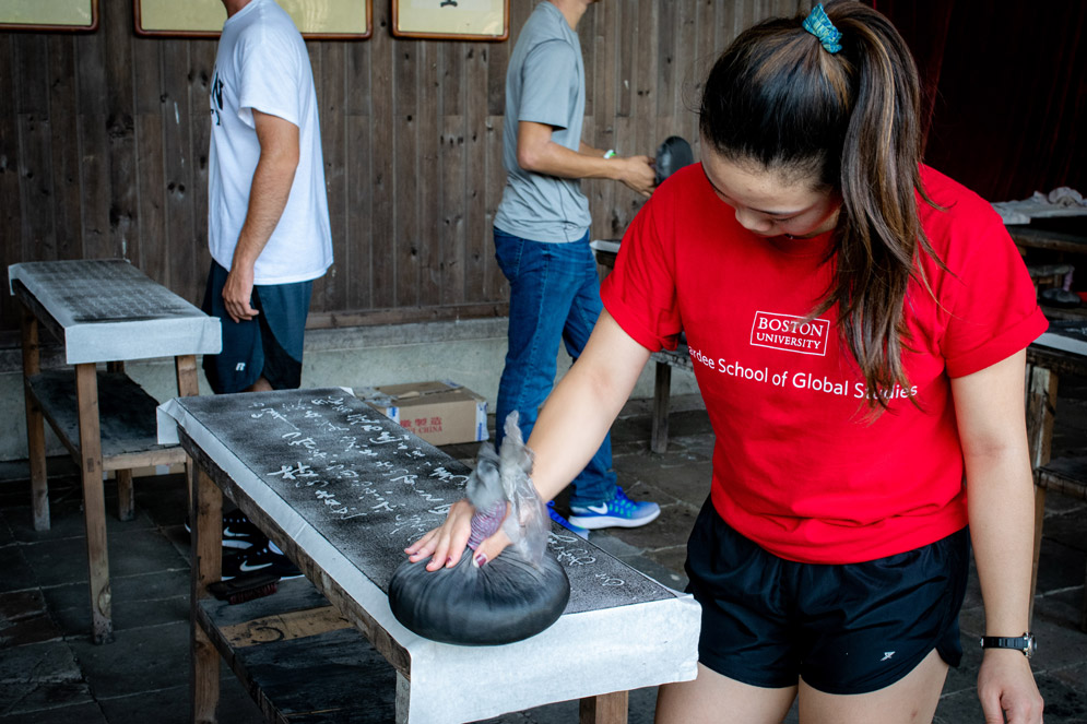 a student wearing a Boston University Pardee School of Global Studies t shirt using traditional asian printmaking tools