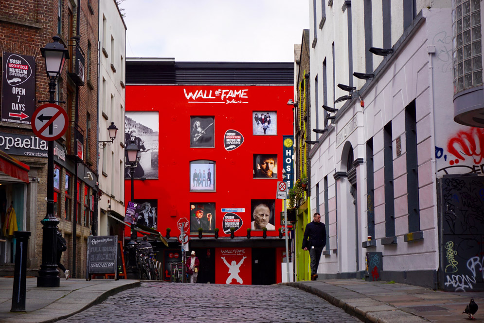 a street that ends with a large red building that says Wall of Fame Dublin