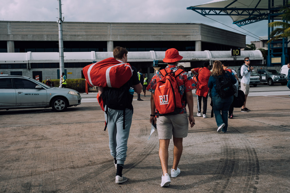 students walk towards a transportation hub, carrying red BU bags