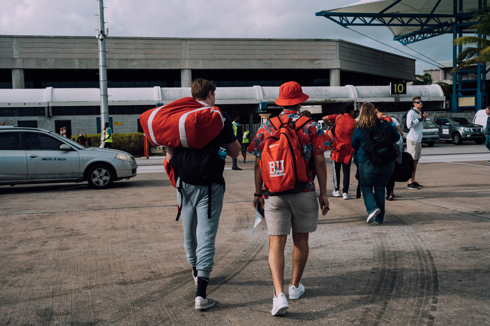 students walk towards a transportation hub, carrying red BU bags