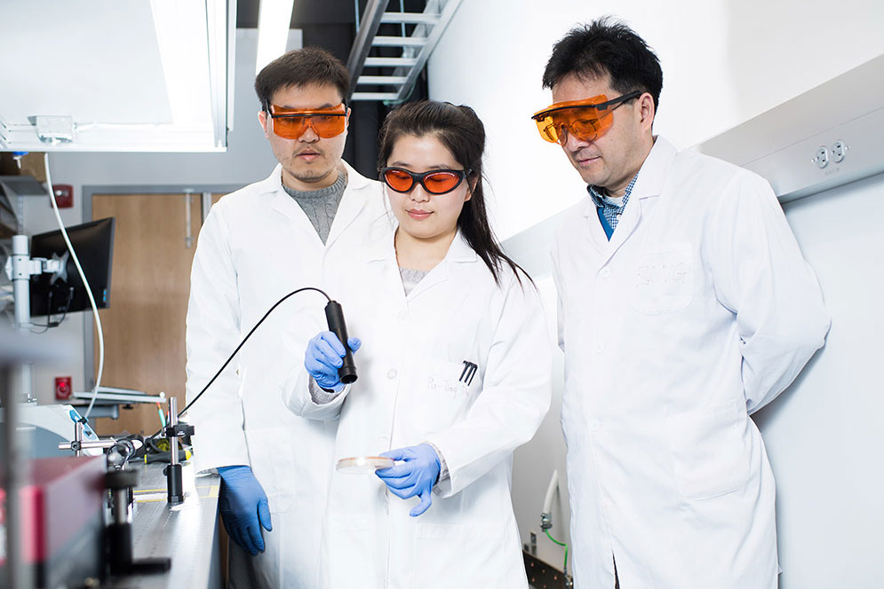 Graduate student, Puting Dong demonstrates the blue light laser therapy MRSA treatment as Dr. Ji-Xin Cheng and post doc Jie Hui look on.