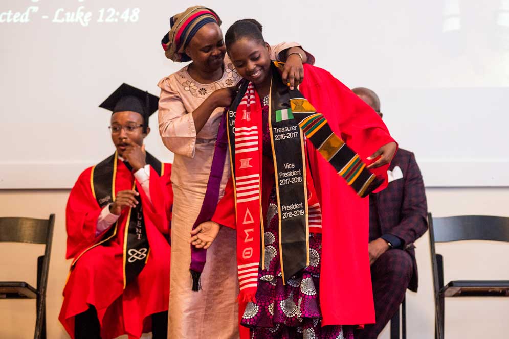 A graduate is draped with a stole