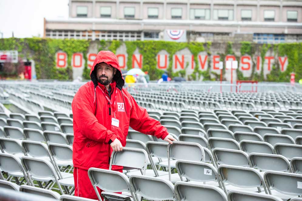 A BU employee aranges chairs on the field