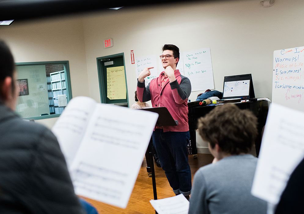 Boston University student Sam DeSoto teaches grade school students how to sing.