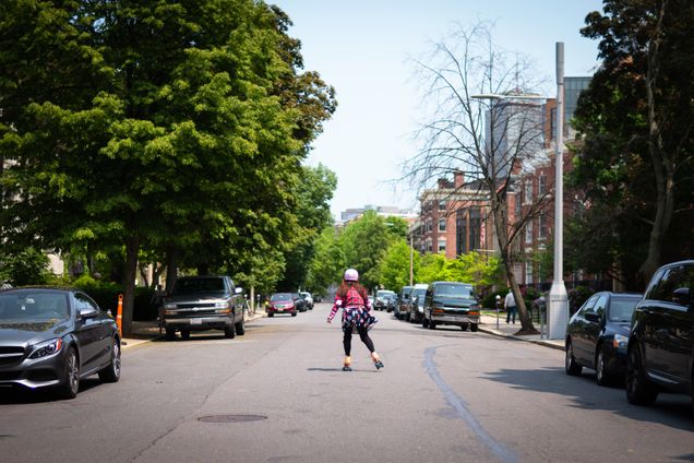 A student roller blades down a quiet street in the summertime