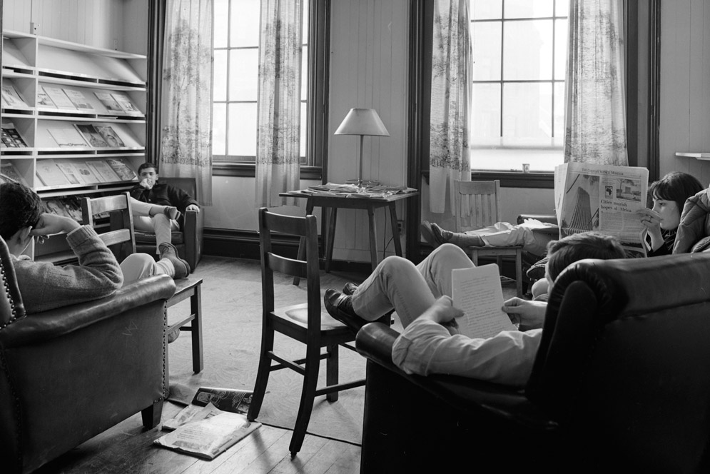 An archival image of students reading and relaxing in a lounge on campus