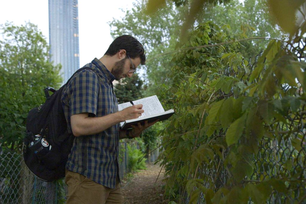 Urban Agriculture class student Jared Kaufman writes in his notebook during a class tour of the Fenway Victory Gardens.