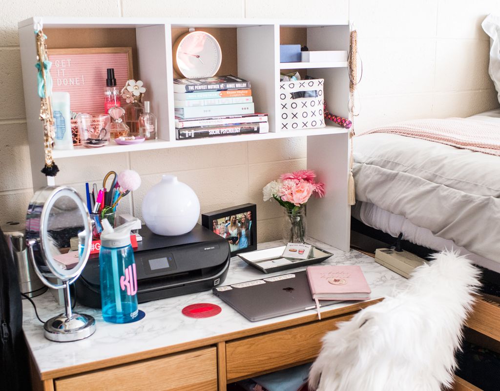 A desk with a laptop, mirror, and other items on it
