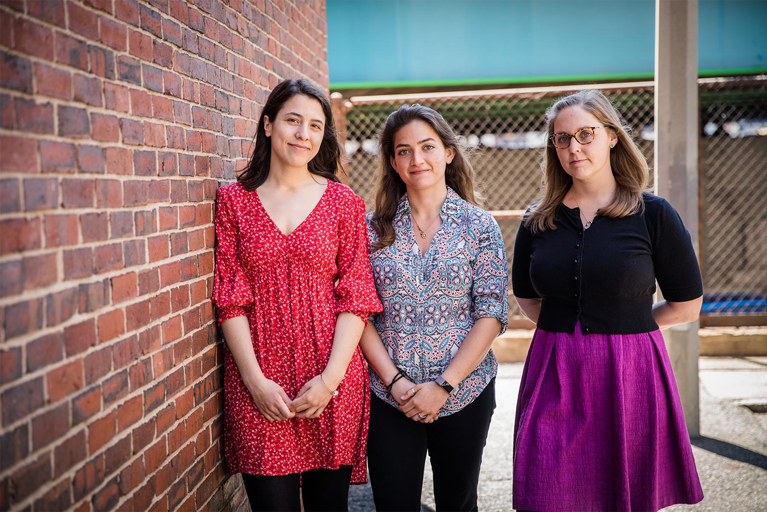 Portrait of Jade La Rochelle, Natalie Petrone, and Emily Briggs next to a brick wall.