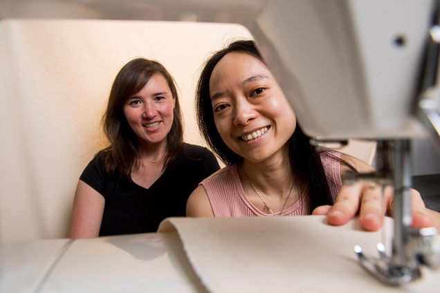 Boston University computer science researchers Emily Whiting and Xiaoting Zhang pose for a portrait behind a sewing machine.