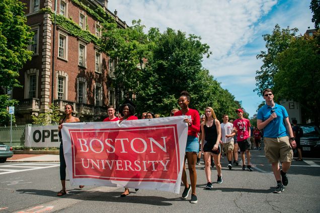 Three African American women carry a Boston University banner leading the Class of 2023 Matriculation parade.