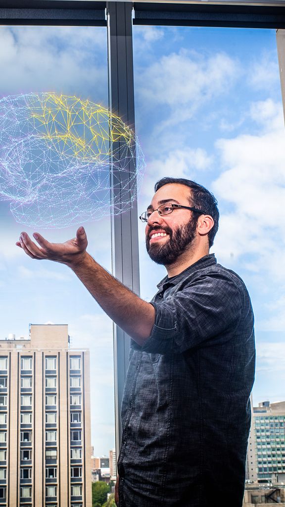 Neuroscience researcher Steve Ramirez holds a digital diagram of a brain.