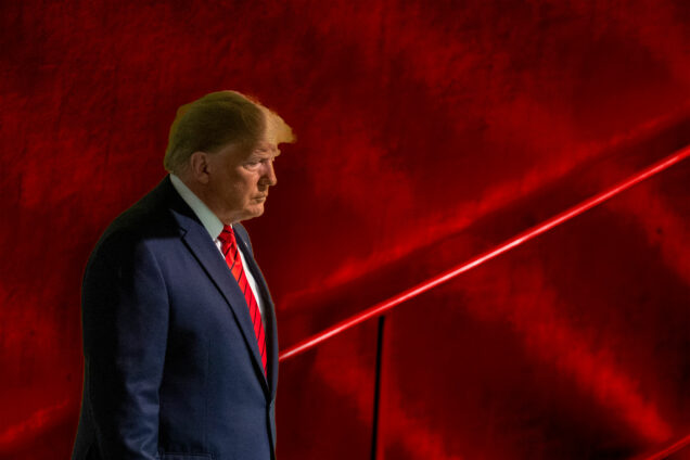 Donald Trump looking pensive in front of a textured red background.
