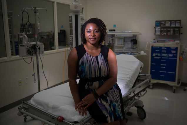 Dr. Tejumola Adegoke, and OBGYN at Boston Medical Center, sitting on a gurney in an operating room.