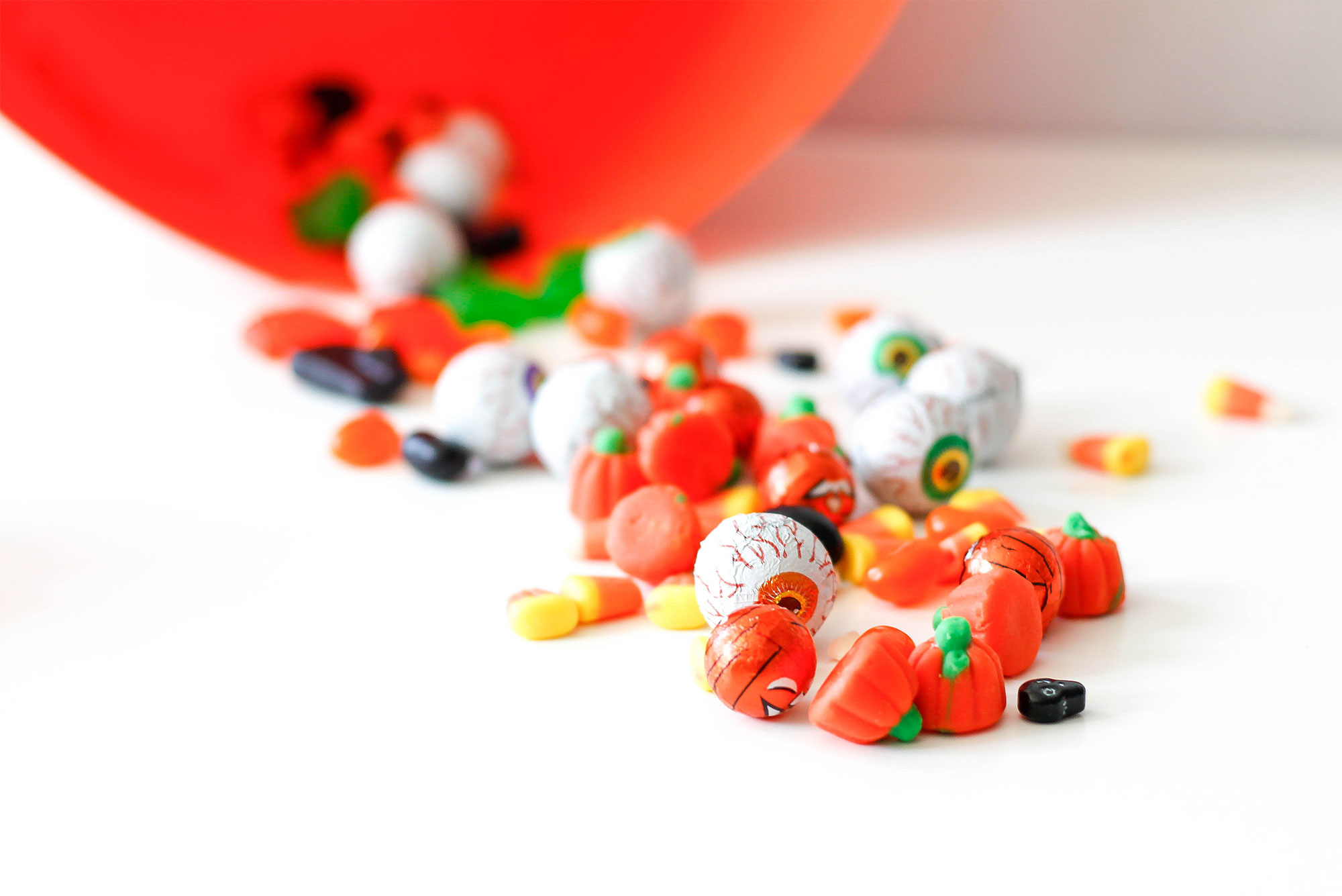 Variety of Halloween candy spilled out of a plastic pumpkin