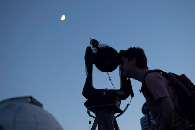 A man gazes through a telescope at the Judson B. Coit Observatory