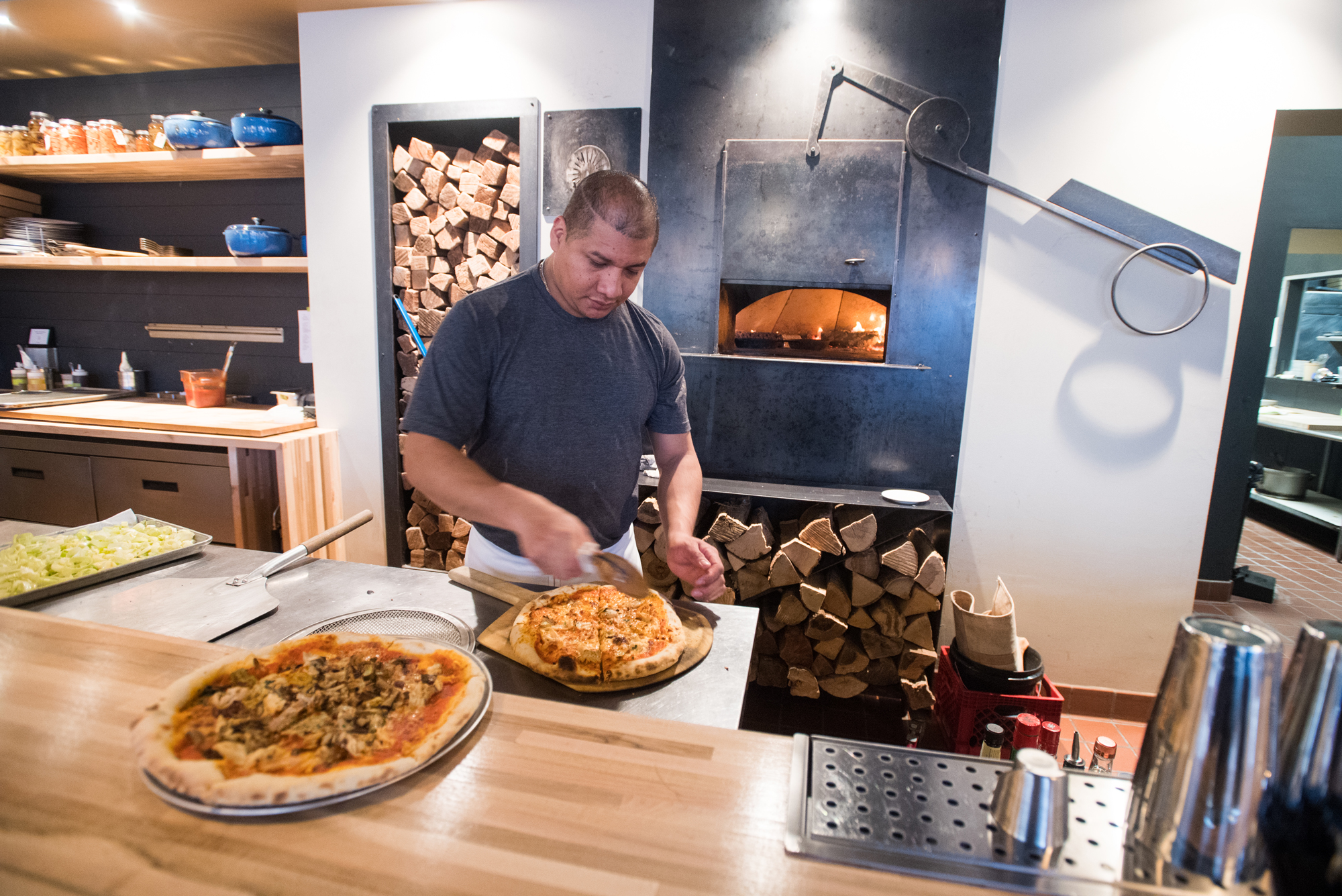 A man cuts pizza at Praire Fire