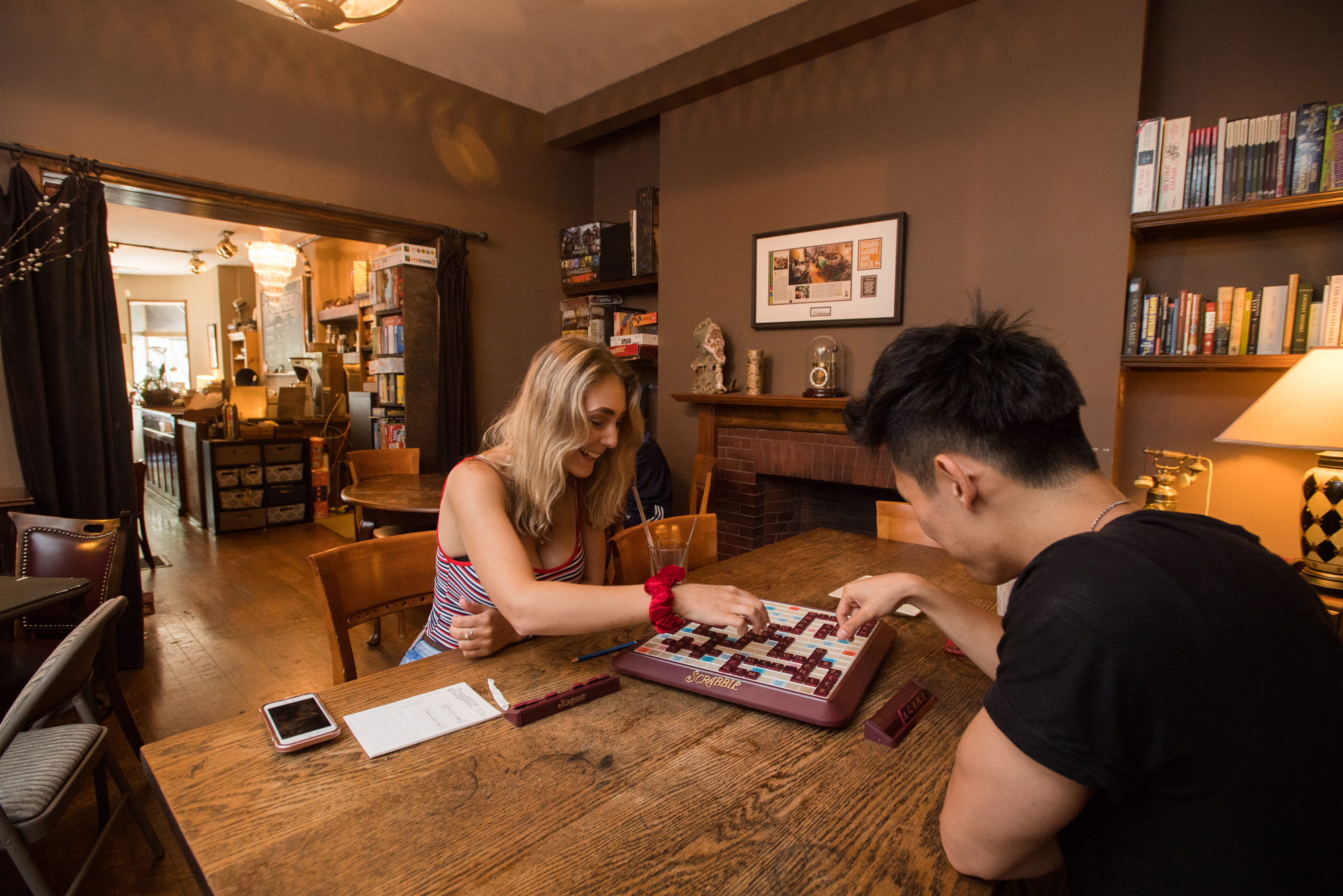 Photo of two people playing Scrabble on a wooden table. 