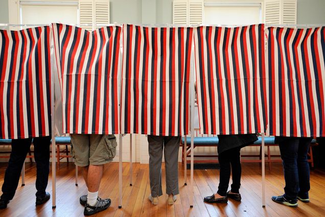 Voters stand behind red, white, and blue striped separators