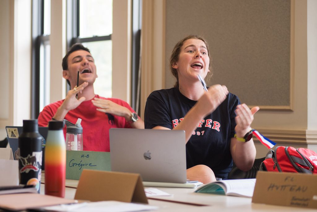 Two students animatedly participate in class acting as 18th-century French assembly members.