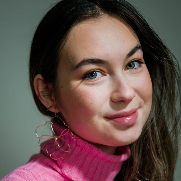 Maya Malekian (COM’20) shows off gold wire earrings in the shape of a flower made by her mom