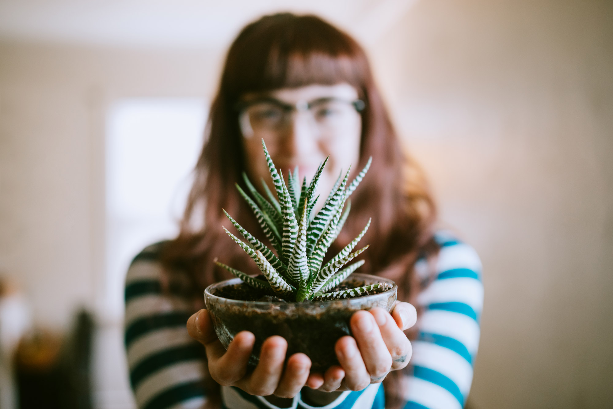 A young woman holds a plant in front of the camera