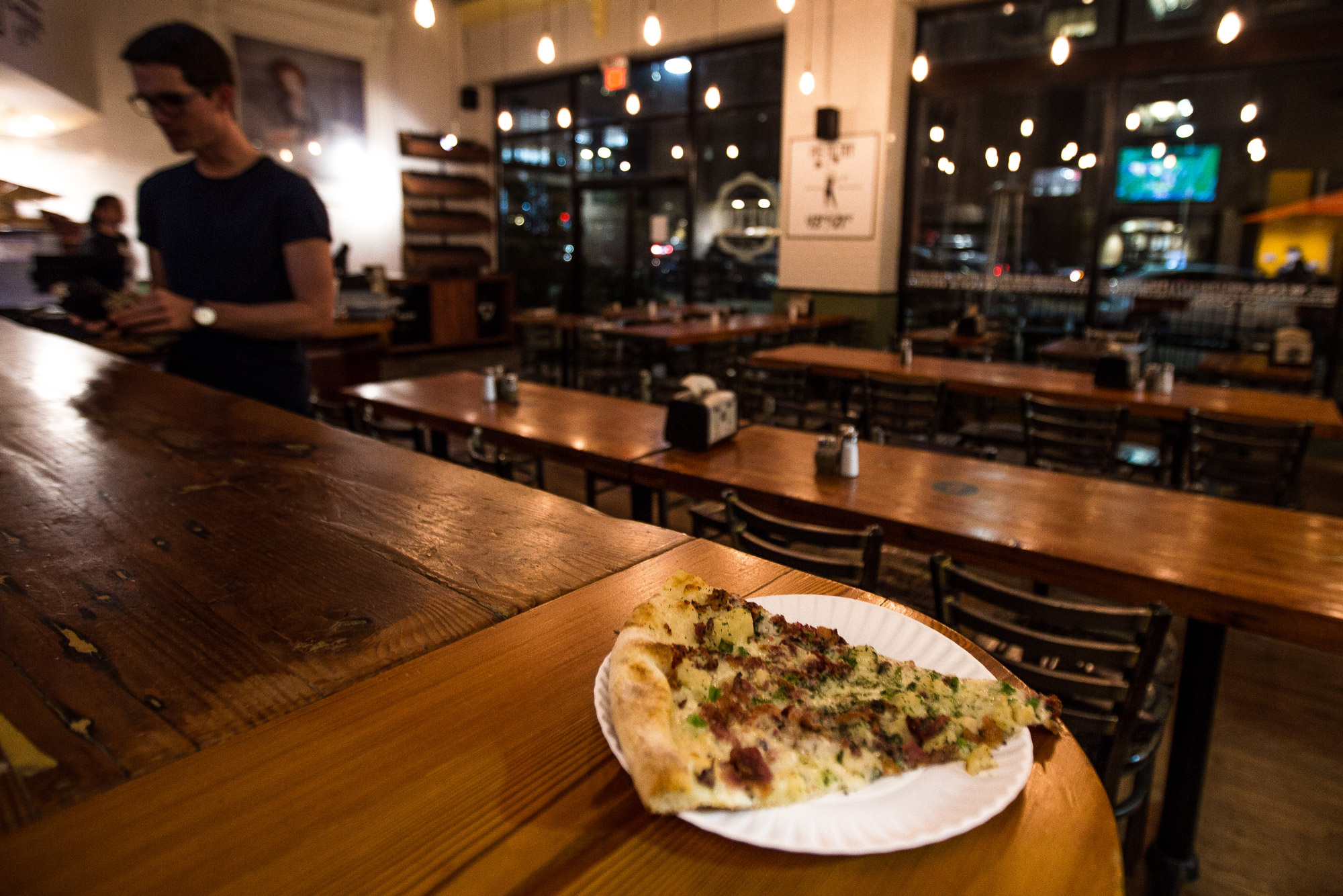 A slice of pizza rests on the counter at Otto late at night