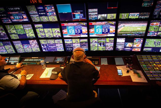 View over the shoulders of sports broadcasting director Bob Fishman watching the screens in the truck while directing an NFL broadcast