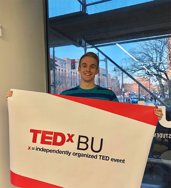 Thomas Rigal holding a TEDxBU sign.