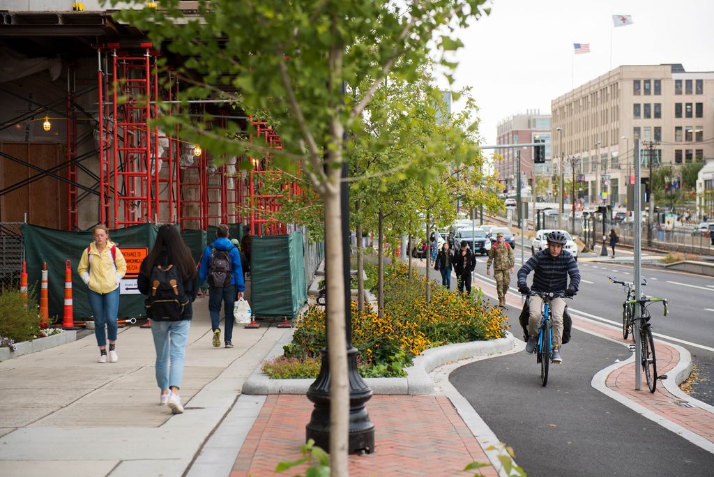 A photo of a bike lane on Commonwealth Avenue. Cyclists and pedestrians are visible in the photo.