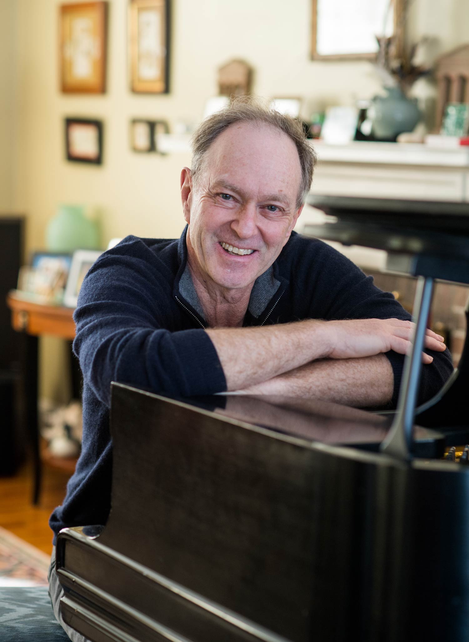 A portrait photo of John Finbury (CAS’77) sitting at his piano.