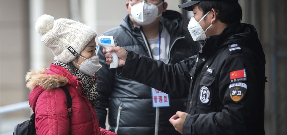 Security personnel check the temperature of a passenger in the Wharf at the Yangtze River on January 22, 2020 in Wuhan, Hubei province, China.
