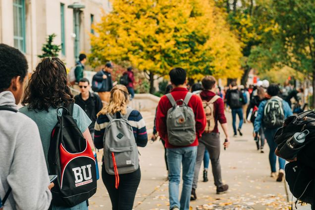 A crowd of Boston University students walk along Commonwealth Avenue on the BU Charles River Campus