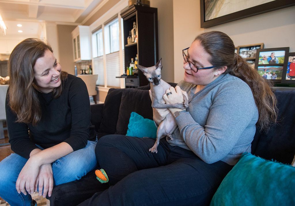 Kirsten Kuhn and Nicole Kutteh sit on the couch with their cat Jada