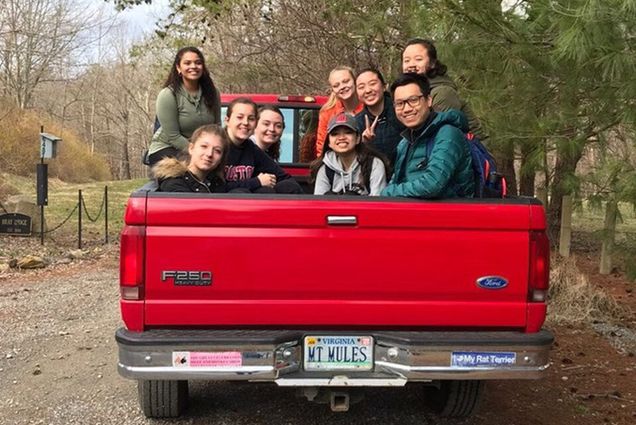 Students on an Alternative Spring Break trip sit in the back of a pick up truck