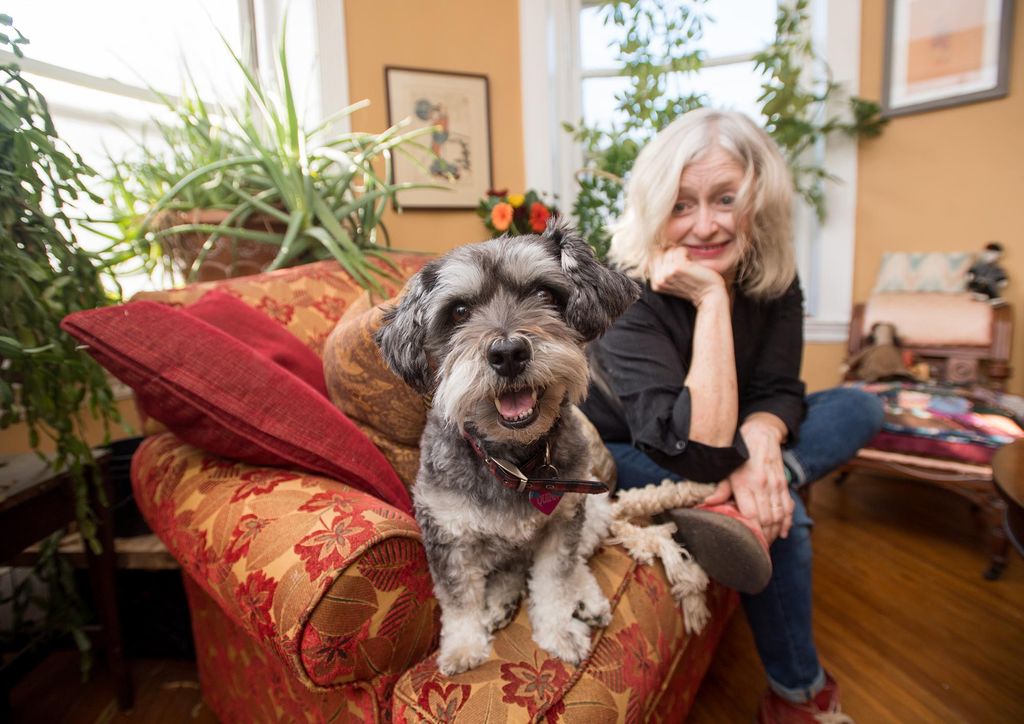 Paula Langton sitting on her couch with her dog, Quinn.