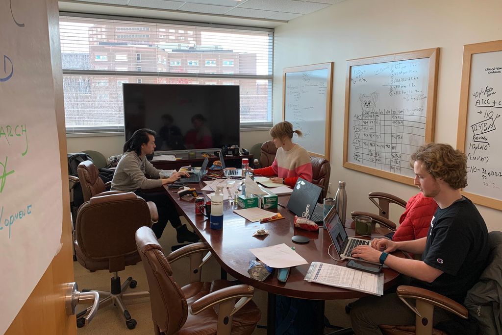 Anthony Yeung, Kim Vanuytsel, and Todd Dowry of the CReM work in the "war room", a conference room that has become mission control for the COVID-19 test development and optimization.